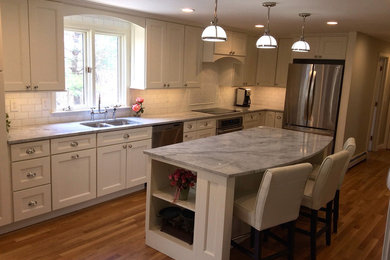 Inspiration for a large contemporary l-shaped medium tone wood floor enclosed kitchen remodel in Boston with an undermount sink, recessed-panel cabinets, white cabinets, quartzite countertops, white backsplash, subway tile backsplash, stainless steel appliances and an island