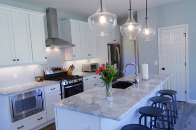 Example of a mid-sized trendy galley eat-in kitchen design in New York with recessed-panel cabinets, white cabinets, an island, a farmhouse sink, marble countertops, stainless steel appliances and gray countertops