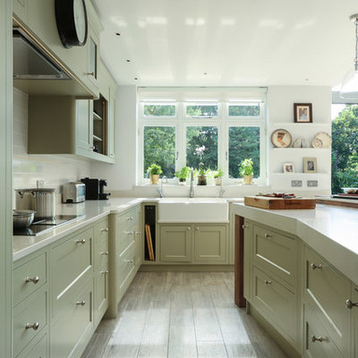Example of a large classic u-shaped kitchen design in London with a farmhouse sink, shaker cabinets, white backsplash and an island