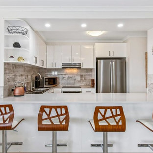 Inspiration for a contemporary u-shaped kitchen in Gold Coast - Tweed with a drop-in sink, flat-panel cabinets, white cabinets, beige splashback, stainless steel appliances and white benchtop.