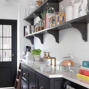 This is an example of a classic kitchen pantry in Surrey with a submerged sink, beaded cabinets, black cabinets, grey floors and white worktops.
