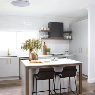 Inspiration for a mid-sized contemporary l-shaped kitchen in Sydney with flat-panel cabinets, grey cabinets, granite benchtops, white splashback, with island, white benchtop, subway tile splashback, panelled appliances, medium hardwood floors and beige floor.
