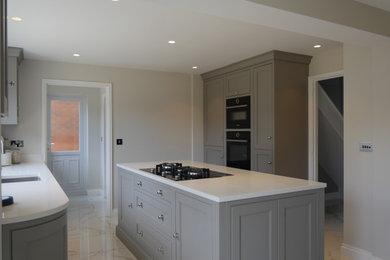 This is an example of a medium sized victorian galley kitchen/diner in West Midlands with an integrated sink, shaker cabinets, grey cabinets, quartz worktops, black appliances, ceramic flooring, an island, white floors and white worktops.