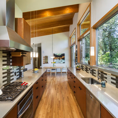 Example of a large trendy galley medium tone wood floor and beige floor eat-in kitchen design in Portland with flat-panel cabinets, gray backsplash, ceramic backsplash, no island, an undermount sink, medium tone wood cabinets, stainless steel appliances and solid surface countertops