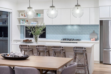 Esempio di una cucina costiera di medie dimensioni con ante in stile shaker, ante bianche, paraspruzzi blu, elettrodomestici in acciaio inossidabile, parquet chiaro, pavimento beige e top bianco