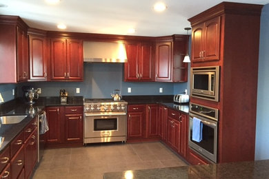 Example of a large classic u-shaped porcelain tile kitchen pantry design in Boston with an undermount sink, raised-panel cabinets, red cabinets, quartz countertops, blue backsplash, stainless steel appliances and an island