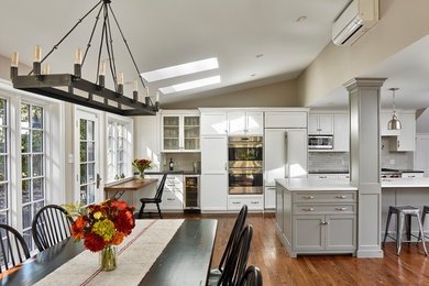 Example of a mid-sized classic galley medium tone wood floor open concept kitchen design in Philadelphia with an undermount sink, gray cabinets, quartz countertops, gray backsplash, subway tile backsplash, stainless steel appliances, an island and shaker cabinets