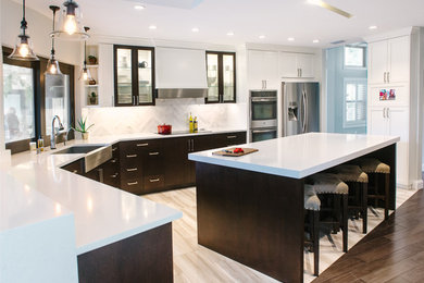 Mid-sized transitional l-shaped porcelain tile eat-in kitchen photo in Tampa with a farmhouse sink, shaker cabinets, white cabinets, quartz countertops, white backsplash, stone tile backsplash, stainless steel appliances and an island