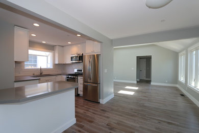 Eat-in kitchen - mid-sized contemporary u-shaped light wood floor eat-in kitchen idea in San Francisco with an undermount sink, recessed-panel cabinets, white cabinets, quartz countertops, white backsplash, ceramic backsplash, stainless steel appliances and an island