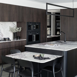 This is an example of a large contemporary u-shaped kitchen in Brisbane with flat-panel cabinets, with island, an undermount sink, dark wood cabinets, multi-coloured splashback, panelled appliances, concrete floors, grey floor and multi-coloured benchtop.