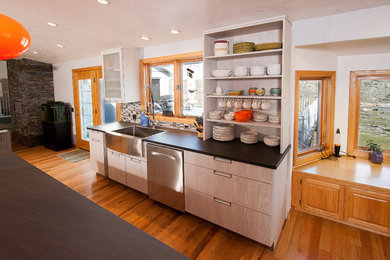 Eat-in kitchen - mid-sized contemporary galley medium tone wood floor and brown floor eat-in kitchen idea in Boise with a farmhouse sink, flat-panel cabinets, gray cabinets, laminate countertops, stainless steel appliances, no island, gray backsplash and ceramic backsplash
