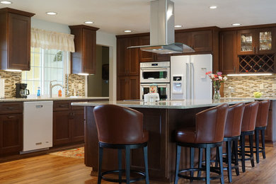 Foto de cocina actual con armarios estilo shaker, puertas de armario de madera en tonos medios, salpicadero multicolor, electrodomésticos blancos y una isla