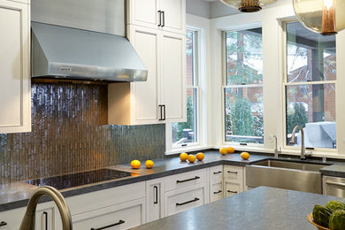 Example of a large trendy l-shaped dark wood floor eat-in kitchen design in San Francisco with a farmhouse sink, recessed-panel cabinets, white cabinets, soapstone countertops, gray backsplash, glass tile backsplash, stainless steel appliances and an island