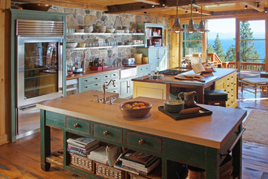 Inspiration för stora rustika u-kök, med en rustik diskho, luckor med profilerade fronter, skåp i slitet trä, träbänkskiva, rostfria vitvaror, mellanmörkt trägolv och flera köksöar