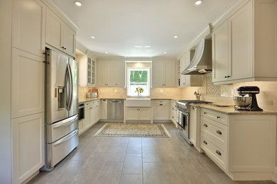 Example of a mid-sized classic u-shaped enclosed kitchen design in Toronto with a farmhouse sink, shaker cabinets and stainless steel appliances