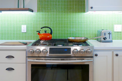 ワシントンD.C.にあるコンテンポラリースタイルのおしゃれなキッチン (シェーカースタイル扉のキャビネット、白いキャビネット、クオーツストーンカウンター、緑のキッチンパネル、モザイクタイルのキッチンパネル、シルバーの調理設備、淡色無垢フローリング、アイランドなし、ベージュの床、白いキッチンカウンター) の写真