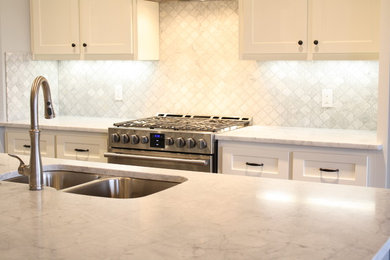 Example of a mid-sized arts and crafts l-shaped ceramic tile open concept kitchen design in Oklahoma City with an undermount sink, shaker cabinets, white cabinets, marble countertops, white backsplash, mosaic tile backsplash, stainless steel appliances and an island