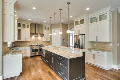 Example of a mid-sized trendy u-shaped medium tone wood floor eat-in kitchen design in Chicago with an undermount sink, recessed-panel cabinets, white cabinets, limestone countertops, beige backsplash, ceramic backsplash, stainless steel appliances and an island