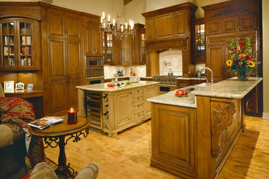 Example of a classic u-shaped open concept kitchen design in Phoenix with an undermount sink, raised-panel cabinets, dark wood cabinets, granite countertops, white backsplash, stone tile backsplash, stainless steel appliances and two islands