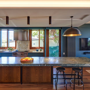 Tropical galley kitchen in Sydney with an undermount sink, flat-panel cabinets, blue cabinets, stainless steel appliances, dark hardwood floors, with island, brown floor, grey benchtop and recessed.
