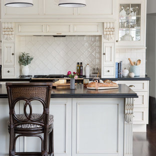 Traditional kitchen in Brisbane with recessed-panel cabinets, beige cabinets, white splashback, dark hardwood floors, with island, brown floor and black benchtop.