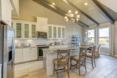 Foto på ett lantligt kök och matrum, med vita skåp, vitt stänkskydd, rostfria vitvaror, ljust trägolv och en köksö