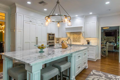 Large transitional u-shaped light wood floor eat-in kitchen photo in Tampa with a drop-in sink, flat-panel cabinets, white cabinets, granite countertops, beige backsplash, ceramic backsplash, stainless steel appliances and an island