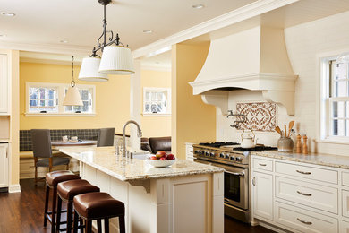Klassisk inredning av ett flerfärgad flerfärgat kök och matrum, med en rustik diskho, luckor med infälld panel, beige skåp, flerfärgad stänkskydd, rostfria vitvaror, mörkt trägolv, en köksö, brunt golv och granitbänkskiva