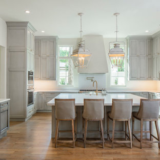 Large traditional kitchen designs - Inspiration for a large timeless u-shaped medium tone wood floor kitchen remodel in Austin with paneled appliances, an island, an undermount sink, recessed-panel cabinets, gray cabinets, white backsplash and white countertops