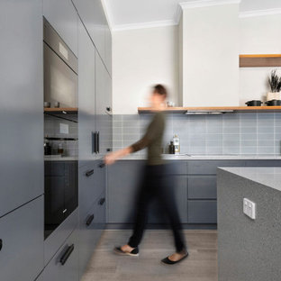 Design ideas for a mid-sized contemporary l-shaped kitchen pantry in Canberra - Queanbeyan with an undermount sink, flat-panel cabinets, blue cabinets, terrazzo benchtops, blue splashback, subway tile splashback, black appliances, laminate floors, with island, beige floor, blue benchtop and vaulted.