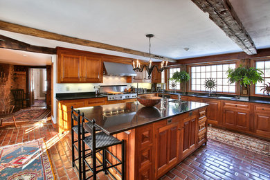 Example of a farmhouse l-shaped terra-cotta tile kitchen design in Boston with an undermount sink, raised-panel cabinets, medium tone wood cabinets and stainless steel appliances
