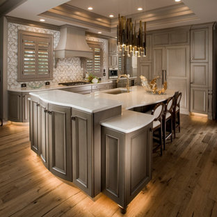 Large traditional open plan kitchen in Wichita with a single-bowl sink, recessed-panel cabinets, beige cabinets, quartz benchtops, beige splashback, porcelain splashback, panelled appliances, medium hardwood floors, with island, brown floor and white benchtop.