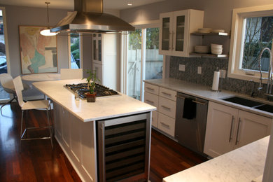 Example of a large mid-century modern u-shaped medium tone wood floor and red floor eat-in kitchen design in Portland with an undermount sink, recessed-panel cabinets, white cabinets, marble countertops, gray backsplash, mosaic tile backsplash, stainless steel appliances, an island and white countertops