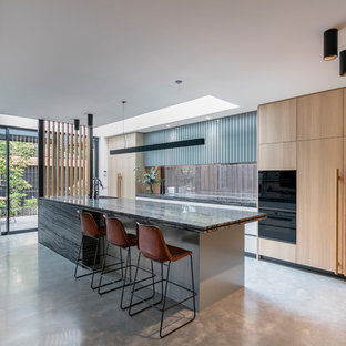 Inspiration for a large contemporary galley open plan kitchen in Melbourne with a drop-in sink, light wood cabinets, window splashback, black appliances, concrete floors, with island, grey floor, flat-panel cabinets and grey benchtop.