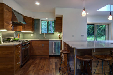 Moderne Wohnküche in L-Form mit Schrankfronten im Shaker-Stil, dunklen Holzschränken, Mineralwerkstoff-Arbeitsplatte und Küchengeräten aus Edelstahl in New York