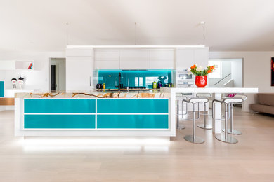 Immagine di una cucina abitabile design con paraspruzzi blu e paraspruzzi con lastra di vetro