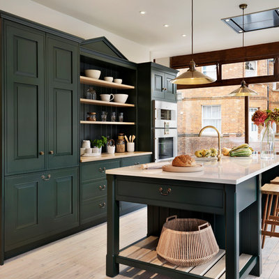 Kitchen - traditional galley light wood floor kitchen idea in Oxfordshire with recessed-panel cabinets, green cabinets, stainless steel appliances and an island
