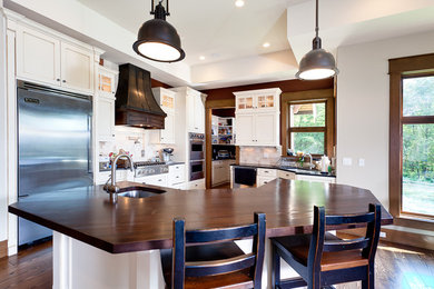 Example of a classic kitchen design in Vancouver with wood countertops, beige backsplash and stainless steel appliances