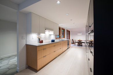 Example of a mid-sized trendy galley light wood floor eat-in kitchen design in Vancouver with an undermount sink, flat-panel cabinets, light wood cabinets, concrete countertops, white backsplash, ceramic backsplash and stainless steel appliances