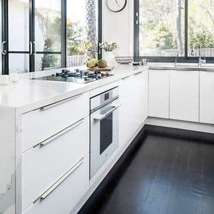 Inspiration for a mid-sized modern u-shaped eat-in kitchen in Melbourne with an integrated sink, flat-panel cabinets, white cabinets, quartz benchtops, black appliances, dark hardwood floors, a peninsula, black floor and yellow benchtop.