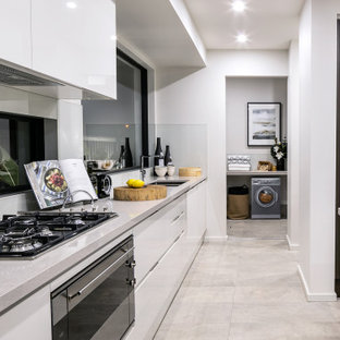 Photo of a large contemporary l-shaped kitchen in Newcastle - Maitland with a double-bowl sink, flat-panel cabinets, white cabinets, window splashback, with island, grey floor and grey benchtop.