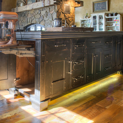 Example of a large mountain style l-shaped medium tone wood floor eat-in kitchen design in Minneapolis with flat-panel cabinets, black cabinets, zinc countertops, paneled appliances, an island and gray countertops