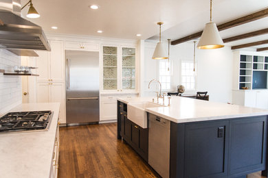 This is an example of a large country u-shaped open plan kitchen in Sacramento with a belfast sink, shaker cabinets, white cabinets, marble worktops, white splashback, metro tiled splashback, stainless steel appliances, medium hardwood flooring, an island, brown floors and white worktops.