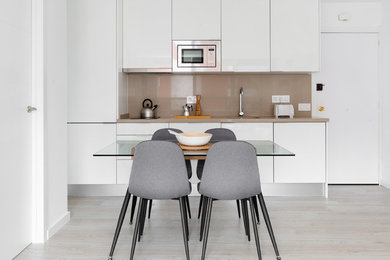 Photo of a scandi kitchen/diner in Other with a single-bowl sink, flat-panel cabinets, white cabinets, brown splashback, light hardwood flooring, beige floors and brown worktops.