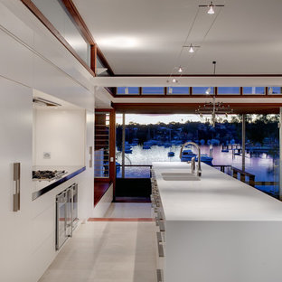 Inspiration for a mid-sized contemporary galley separate kitchen in Sydney with flat-panel cabinets, white cabinets, stainless steel appliances, an integrated sink, white splashback and travertine floors.