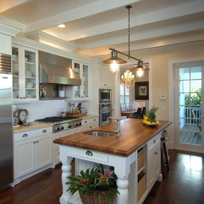 Example of a mid-sized classic galley dark wood floor enclosed kitchen design in Miami with subway tile backsplash, wood countertops, white cabinets, white backsplash, stainless steel appliances, a single-bowl sink, shaker cabinets and an island