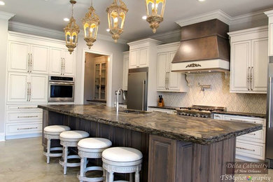 This is an example of a large traditional l-shaped kitchen/diner in New Orleans with a submerged sink, raised-panel cabinets, white cabinets, beige splashback, glass tiled splashback, stainless steel appliances and an island.