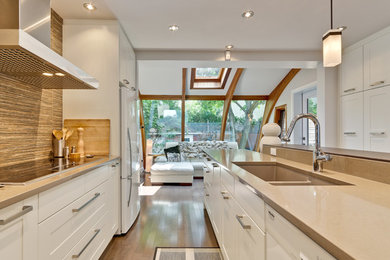 Example of a mid-sized transitional u-shaped medium tone wood floor and brown floor eat-in kitchen design in Montreal with an undermount sink, flat-panel cabinets, white cabinets, wood countertops, brown backsplash, wood backsplash, white appliances and an island