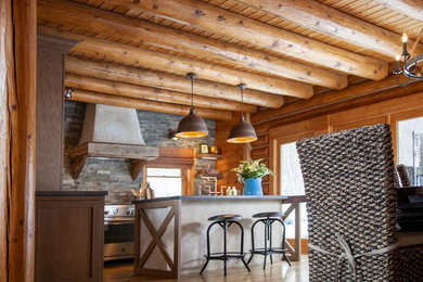 Inspiration for a large rustic l-shaped medium tone wood floor and brown floor eat-in kitchen remodel in Boston with a farmhouse sink, shaker cabinets, medium tone wood cabinets, soapstone countertops, gray backsplash, stone tile backsplash, stainless steel appliances, an island and gray countertops