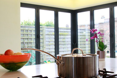 Esempio di una cucina contemporanea con lavello a doppia vasca, ante lisce, ante bianche, top in superficie solida, paraspruzzi verde, paraspruzzi con lastra di vetro, elettrodomestici da incasso e parquet chiaro
